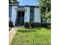 Two-story condo building features blue and white facade, landscaped yard, and a welcoming entrance at 220 Cypress Ln # 220, Oldsmar, FL 34677