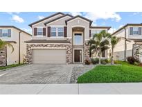 Charming two-story home featuring a stone facade, manicured lawn, and paver driveway at 3071 Marine Grass Dr, Wimauma, FL 33598