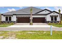 Charming exterior featuring stone accents, dark wood garage doors and a well-manicured lawn at 35579 Stableton Ln, Zephyrhills, FL 33541