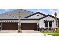 Beautiful home featuring a three-car garage, a well-manicured lawn, and decorative stone accents at 35579 Stableton Ln, Zephyrhills, FL 33541