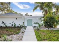 Charming home featuring a stylish walkway leading to a light blue front door and lush, tropical landscaping at 3801 Dr Martin Luther King Jr N St, St Petersburg, FL 33703