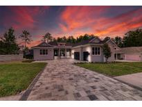 Stunning one-story home with a patterned paver driveway and a two-car garage set against a colorful sunset at 4522 Majestic Hills Loop, Brooksville, FL 34601