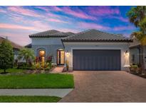 Charming one-story home with a paver driveway, lush landscaping, and a two car garage at 5410 Morey Farms Loop, Palmetto, FL 34221