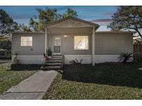 Charming single-story home featuring a covered porch, gray siding, and well-maintained landscaping at 10501 Bay Hills Cir, Thonotosassa, FL 33592