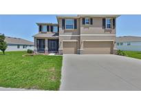 Inviting two-story home featuring a well-manicured lawn and attached two-car garage with tan paint and black shutters at 11924 Brighton Knoll Loop, Riverview, FL 33579