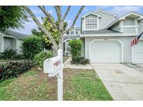 Charming townhome featuring a white garage door, a manicured lawn, and an American flag at 2456 Alhambra St, Clearwater, FL 33761