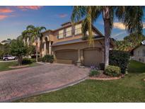Beautiful two-story home with a three-car garage and a brick driveway, complemented by lush landscaping and palm trees at 2614 Brookforest Dr, Wesley Chapel, FL 33544