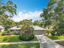 Charming single-story home with a well-manicured lawn, complemented by mature trees and lush landscaping at 2742 Sea Pines E Cir, Clearwater, FL 33761