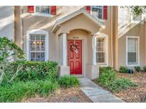 Charming townhome front door with red door, wreath and small front garden at 30140 Barnaby Ln, Wesley Chapel, FL 33543