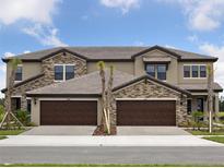 Beautiful townhouse showcasing a stone facade and two-car garage, offering a modern and stylish curb appeal at 35609 Stableton Lane, Zephyrhills, FL 33541