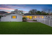 Charming single-story home featuring a well-manicured lawn and a classic white picket fence at dusk at 4709 W Fair Oaks Ave, Tampa, FL 33611
