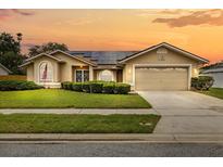 Charming single-story home with a well-maintained lawn, solar panels and a two-car garage at sunset at 5405 El Cerro Dr, New Port Richey, FL 34655