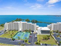 Stunning aerial view of a waterfront condo community, tennis courts, and picturesque ocean views at 5915 Sea Ranch Dr # 202, Hudson, FL 34667