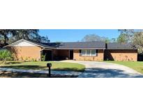 Charming brick home featuring a well-manicured lawn and a spacious driveway on a sunny day at 7014 Doreen St, Tampa, FL 33617