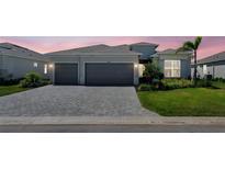 Lovely single-story home featuring a two-car garage, paver driveway, manicured lawn, and beautiful landscaping at 8589 Saint Kitts Cir, Englewood, FL 34224