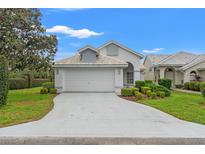 Charming single-story home with a well-manicured lawn, lush landscaping, and a two-car garage with white tile roof at 9188 Rhett Ln, Weeki Wachee, FL 34613