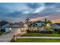 Charming single-story home with lush landscaping and a two-car garage at dusk at 1028 Wyndham Way, Safety Harbor, FL 34695