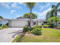 Charming single-story home featuring a lush landscaped front yard, inviting curb appeal, and a two-car garage at 2113 Malcolm Dr, Palm Harbor, FL 34684