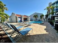 Community pool with plenty of lounge chairs and lush landscaping offers a relaxing oasis at 320 Medallion Blvd # G, Madeira Beach, FL 33708