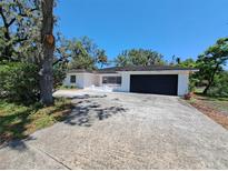 Charming single-story home with a brick facade, mature trees, and a spacious driveway at 406 Bullard Pkwy, Temple Terrace, FL 33617