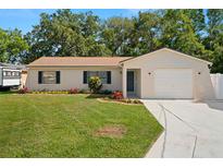 Charming single story home featuring manicured lawn, colorful landscaping, attached garage, and neutral color palette at 4549 Ontario Dr, New Port Richey, FL 34652