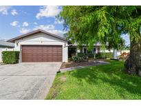 Charming single-story home with a well-maintained lawn and brown garage door, complemented by a mature, shady tree at 6903 Cedar Ridge N Dr, Pinellas Park, FL 33781