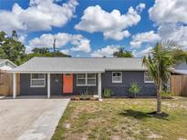 Charming single-story home with a well-manicured lawn and a vibrant, welcoming orange front door at 8497 Portulaca Ave, Seminole, FL 33777