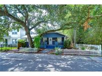 Charming home featuring mature trees, a welcoming porch and a classic white picket fence at 902 W Columbus Dr, Tampa, FL 33602