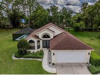 Beautiful home with a well-manicured lawn and a screened-in pool area in the backyard at 11368 Copley Ct, Spring Hill, FL 34609