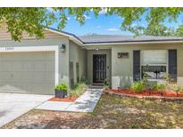 Welcoming front entrance with a solid door, a well-manicured garden bed, and an attached two-car garage at 13643 Tramore Dr, Odessa, FL 33556