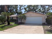 Charming single-story home featuring a two-car garage, brick accents, and lush palm tree landscaping at 1538 S Lake Ave, Clearwater, FL 33756