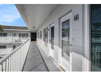 White painted hallway with white railing and blue sky, leading to the condo entrances in a well maintained community at 2002 Australia E Way # 66, Clearwater, FL 33763