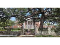 Elegant brick home behind a stone wall and iron gate, shaded by a mature oak tree at 5002 S Shore Crest Cir, Tampa, FL 33609