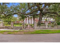 Brick home behind wall with wrought iron fence and gate, large oak tree hangs over the front at 5002 S Shore Crest Cir, Tampa, FL 33609