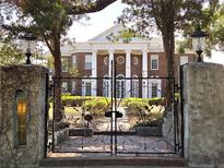 Elegant red brick home featuring stately columns, a gated entrance and lush landscaping at 5002 S Shore Crest Cir, Tampa, FL 33609