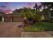 Charming home with a brick driveway, complemented by tropical landscaping and a serene residential neighborhood at 5101 Hartwell Loop, Land O Lakes, FL 34638
