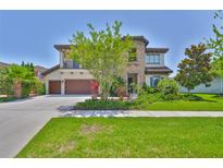 Stunning two-story home featuring a lush lawn, mature tree, and an attached two-car garage at 6913 Park Strand Dr, Apollo Beach, FL 33572