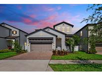 Beautiful gray two-story home with a brick driveway and colorful landscaping at 7703 S Kissimmee St, Tampa, FL 33616