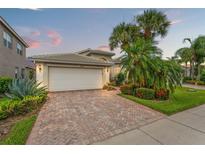 Charming home featuring a paver driveway, lush landscaping, and a two-car garage with beautiful curb appeal at 5009 Sandy Brook Cir, Wimauma, FL 33598