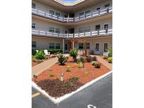 Exterior view of a multi-story building with landscaped courtyard, white Adirondack chairs, and walkways at 5530 80Th N St # A306, St Petersburg, FL 33709