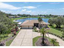 Beautiful lakefront home featuring a circular driveway, mature landscaping, and an oversized three-car garage at 8827 Scout Lake Ct, New Port Richey, FL 34654