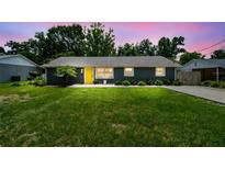 Charming home featuring a yellow door, well-maintained lawn, and lush green bushes at 1005 Monroe St, Plant City, FL 33565