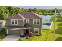 Charming two-story home features a landscaped yard with a lake view and attached two-car garage at 14560 Haddon Mist Dr, Wimauma, FL 33598
