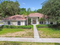 Stunning single-story home featuring mature landscaping, a beautiful tile roof, and a welcoming entryway at 3351 Bristol Pl, Tarpon Springs, FL 34688