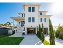 Modern white three-story home with a spacious covered parking area and well-manicured front lawn at 3752 Arkansas Ne Ave, St Petersburg, FL 33703