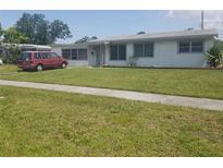 Charming single-story home with a well-maintained lawn and red van parked in the driveway at 4409 W Wyoming Ave, Tampa, FL 33616