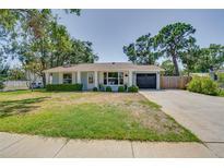 Charming single-story home with a well-manicured lawn, attached garage and mature trees at 4700 Chancellor Ne St, St Petersburg, FL 33703