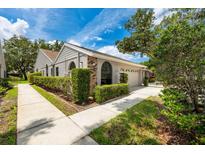 Well-maintained home featuring a lush green hedge, walkway and attached garage at 5524 Salem Square N Dr, Palm Harbor, FL 34685