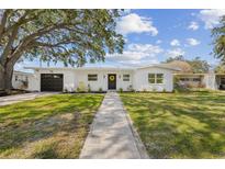 Charming single-story home featuring a well-manicured lawn, a paved walkway, and a welcoming front door at 75 New Jersey Dr, Dunedin, FL 34698