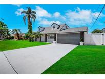 Charming home featuring a manicured lawn, mature palm trees, and a spacious two-car garage at 8711 Thornwood Ln, Tampa, FL 33615